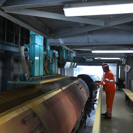  Workers in front of train in a hall that is loaded with grain