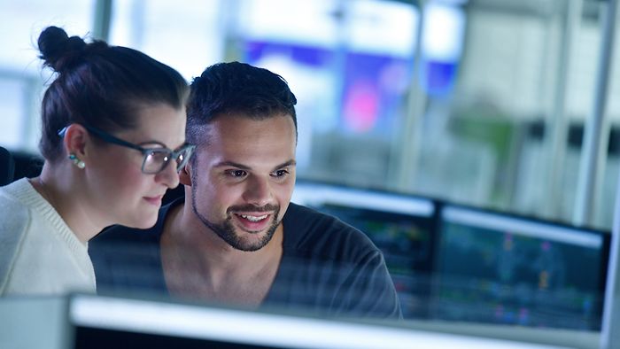 Two employees watching a screen